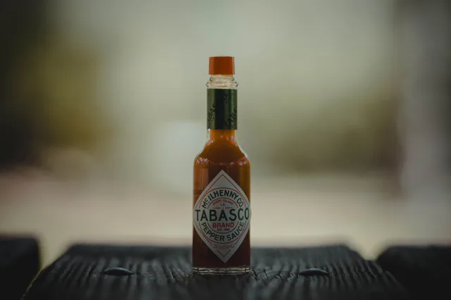 Close-up of a Tabasco sauce bottle on a wooden surface, emphasizing its spicy essence. Hot Sauce Brand Canada Cost: 1,000-Bottle Production Budget