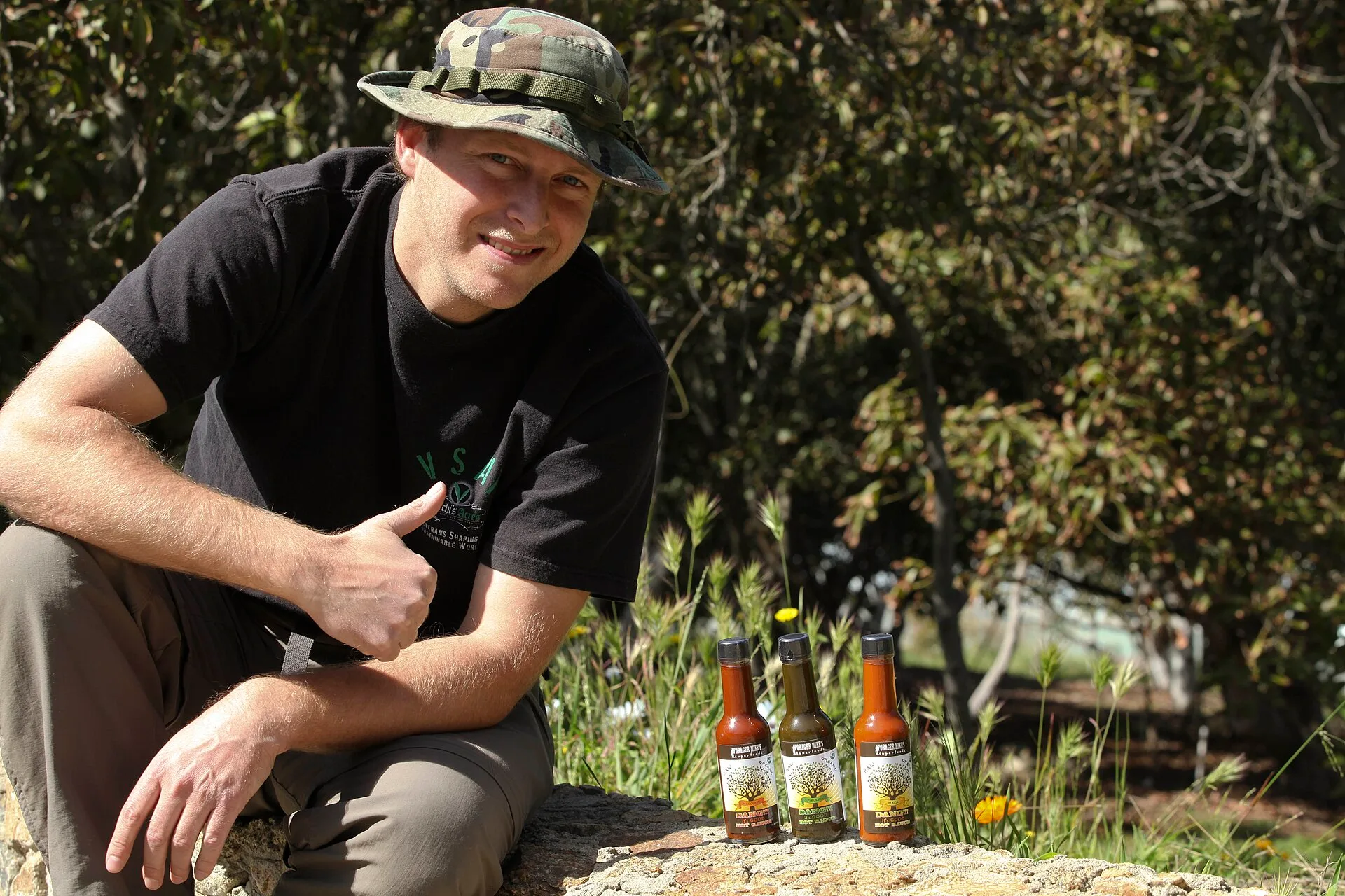Mike N. Hanes, chief executive officer of Forger Mike Superfoods, poses for a photograph next to three bottles of his lastest success; "DANG !!! it's good hot sauce," at Archis Acres, March 7. Sauce making mistakes: the stage ladder from bench to shelf